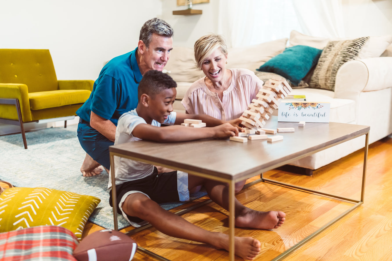 Two adults and a child playing Jenga together at living room table