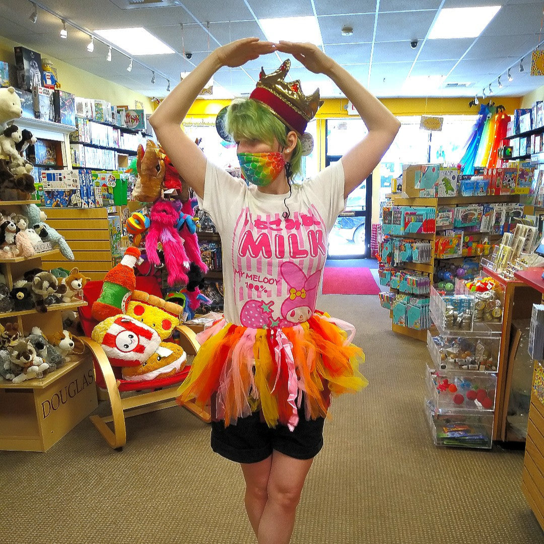 Ross, slender with bright green hair, poses in some of Boing!'s dress up items, a multicolored tutu and fabric crown.